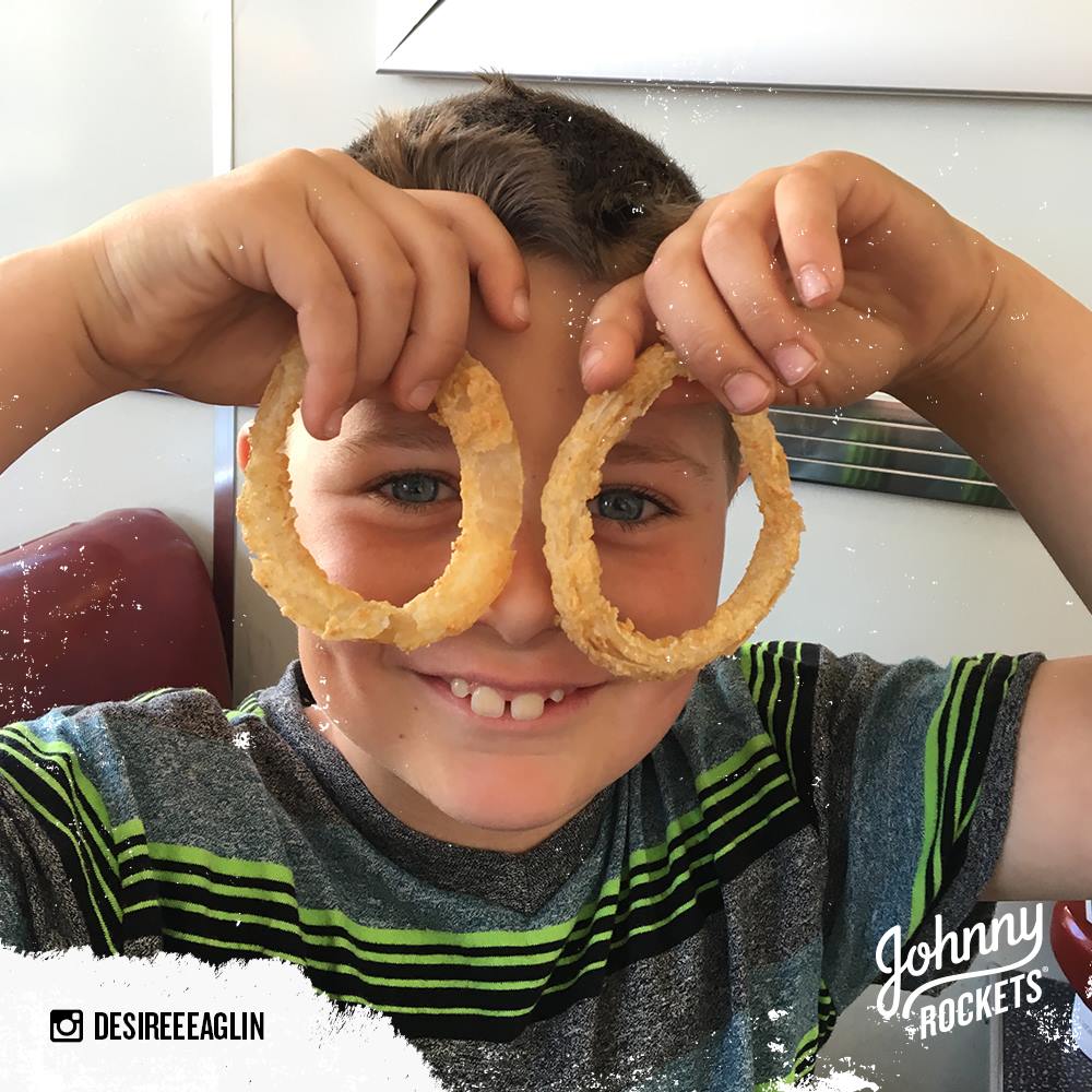 Photo of child holding onion rings in front of eyes pretending they are eyewear at Johnny Rockets in Kent, Washington.