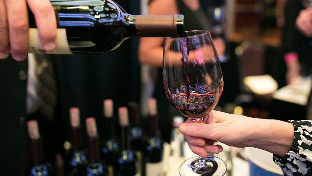 Photo of wine being poured into a glass being held by a hand taken during Kent, WA wine walk