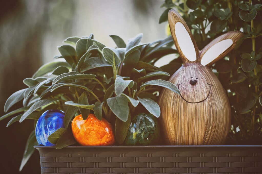 Photo of easter eggs and a hand crafted easter bunny made of wood hiding in a planter